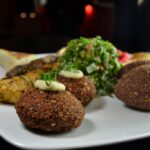 A vibrant Middle Eastern dish with falafel, kebabs, tabbouleh on a plate.